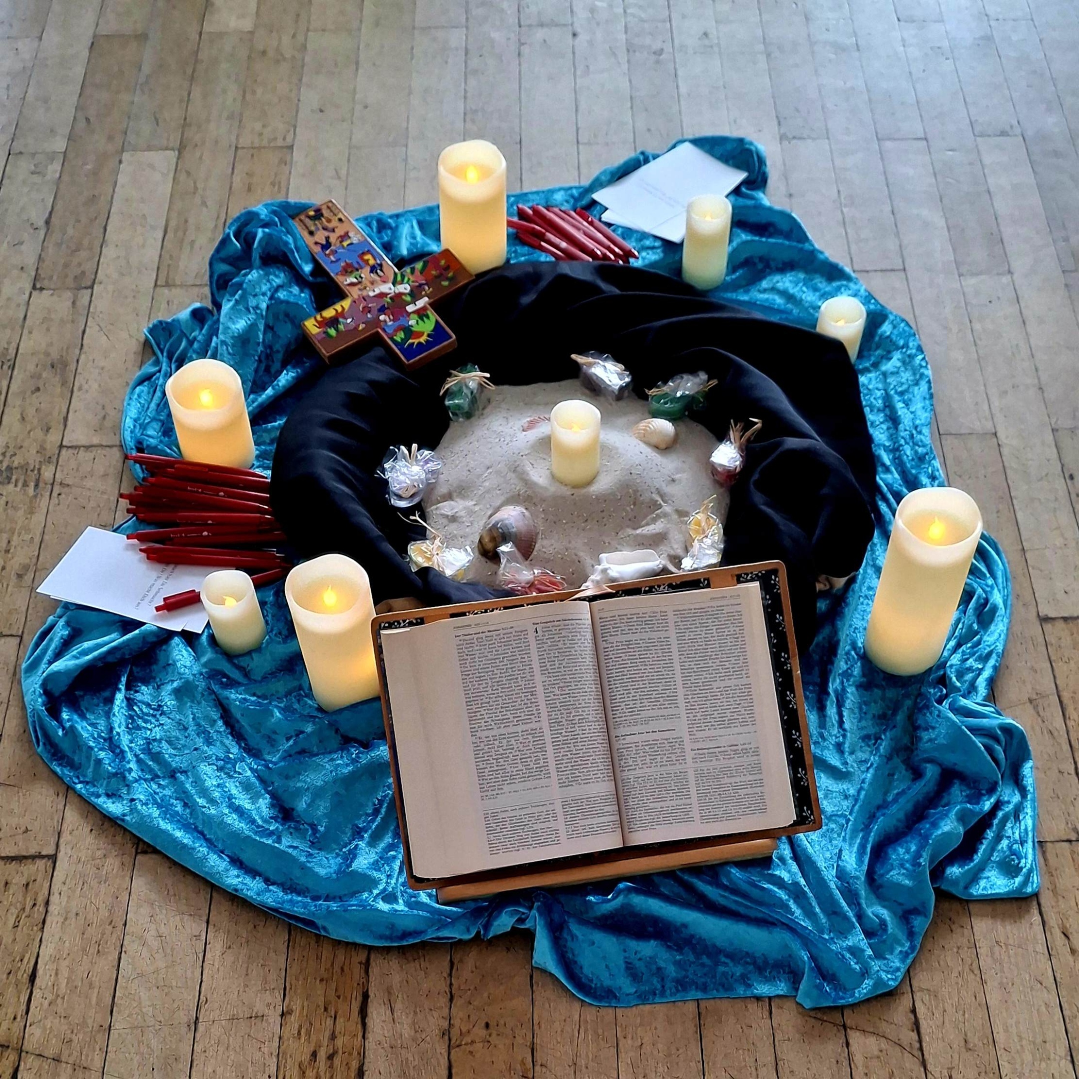 Gestaltete Mitte mit Bibel, Kerzen und KHG-Kreuz